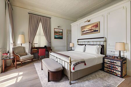 Deluxe Room (ca. 30-45qm) Die Eleganz des historischen Erbes steht hier im Vordergrund, mit einem Doppelbett mit Kopf- und Fußteil aus Messing. Gedämpfte Töne von Taupe und Antikweiß werden durch restaurierte Holzböden mit einem neutralen Teppich, einem Schreibtisch und orientalischen Einrichtungsgegenständen unterstrichen. Das marmorierte Badezimmer hat zwei Waschtische, eine freistehende Badewanne und eine begehbare Dusche. Blick auf den Innenhof der Istanbuler Villen.
