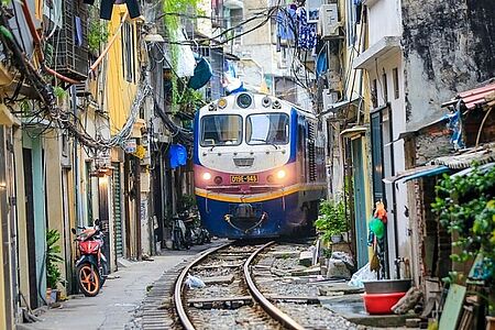 Die berühmte Train Street in Hanoi Die Zugstraße in Hanoi ist ein pulsierendes Spektakel, das den Atem stocken lässt. Nur wenige Zentimeter trennen den vorbeidonnernden Zug von den farbenfrohen Häusern und charmanten Cafés. Wenn die Sirene ertönt, hält die Gasse den Atem an, und die Spannung steigt spürbar.