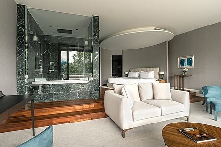 Classic Junior Suite (47-108 qm) Die Junior-Suiten „Classic“ zeichnen sich durch eine komfortable Raumaufteilung und Ausstattung aus, was Ihren Aufenthalt bei uns zu einem besonders stilvollen Erlebnis macht. Der großzügige Sitzbereich, ein begehbarer Kleiderschrank, Bad mit Badewanne und Dusche, weite Fensterfronten und die atemberaubende Aussicht sorgen für maximalen Komfort. Einige Suiten verfügen über einen Balkon.