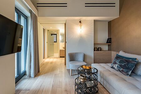 Mystras Suite (ca. 55 - 67 qm) Die eleganten und geräumigen Suiten bieten neben dem großzügigen Schlafraum einen Sitzbereich sowie ein aus Onyx und Marmor gestaltetes Luxusbad mit Dampfdusche und Badewanne. Von der Veranda sowie der separaten Terrasse genießen Sie einen traumhaften Blick über das grüne Tal und die angrenzenden Berge.