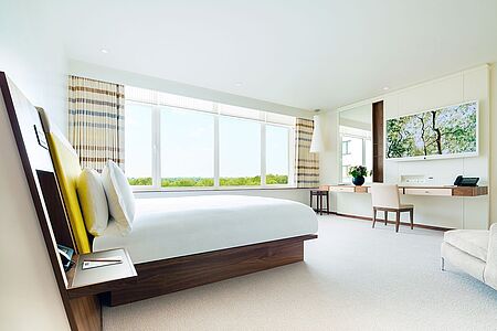 Junior Park Suite (ca. 35 qm) In den Junior Park Suiten reichen die Fenster vom Boden bis zur Decke und durchfluten so den Raum mit Licht, das die Farben der Suite zum Leuchten bringt. Der offene Raum verfügt über Mokka-Chenille-Polsterung die beruhigende Töne in den Raum bringt und eine weiße Keramik-Pendelleuchte bringt das Gefühl von Häuslichkeit in die Suite.