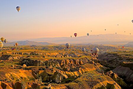 Heißluftballonfahrt  Der Wind trägt Sie nach oben und bestimmt die Richtung. Sie schweben über Felder, Felsen und Feenkamine oder mitten durch die Canyons. Eine Ballonfahrt in Kappadokien ist einfach himmlisch. Eine Stunde vor Sonnenaufgang werden Sie abgeholt und fahren zum Startpunkt Ihres “fliegenden Teppichs”. Bevor Sie abheben, gibt es frischen Kaffee und Kekse.