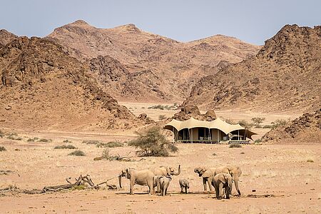 Hoanib Skeleton Coast Camp Eingerahmt von zerfurchten Hügeln und südlich des trockenen Flussbetts des Hoanib Rivers begrüßt das exklusive Hoanib Skeleton Coast Camp an der Nordwestküste Namibias seine Gäste. Es liegt im nördlichen Teil der privaten Palmwag-Konzession und grenzt an den Skeleton Coast Nationalpark.