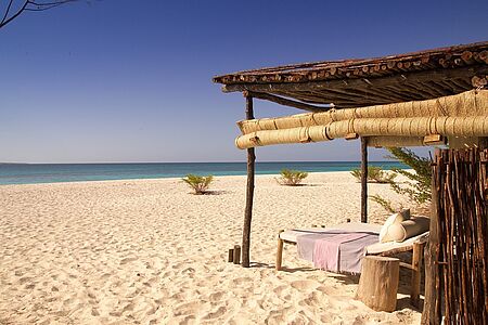 Mnemba Island Lodge Eine Symphonie der Farben - das Meer so kristallklar und türkisblau, der feinsandige Sandstrand so weiß wie Schnee, die tropische Vegetation im sattesten Grün und Sonnenuntergänge in schimmernd goldenen Rottönen - hier auf Mnemba Island vereinen sie sich zur vollendeten Harmonie. In der Architektur der traumhaften Cottages spiegelt sich die Natur wider.
