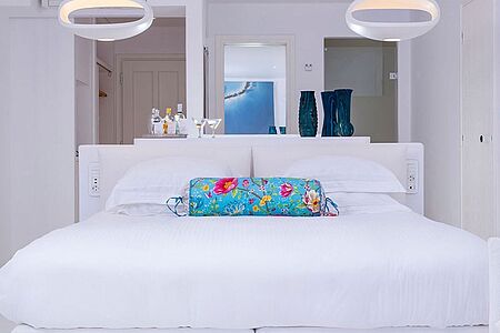 Nissos Suite (ca. 40 qm) In den Nissos Suiten überwiegt die Farbe Weiß, angelehnt an die einmalige Ästhetik der Insel. Neben dem Marmor-Badezimmer und dem Privatbalkon mit Meerblick kommen bis zu drei Erwachsene in den Genuss mehrerer Kunstobjekte, feinster Textilien und High-Tech-Komfort.