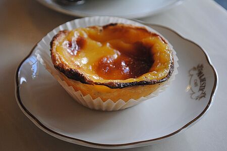 Besuch der Confeitaria Pasteis de Belem In Lissabon ist nur gewesen, wer die unwiderstehlichen Sahnetörtchen Pastéis de Nata probiert hat. Die besten gibt es in der Confeitaria Pasteis de Belem. Und auch, wenn die Tram 15E immer rappelvoll ist: die Fahrt lohnt sich! Sollten Sie im Café keinen Platz bekommen, stellen Sie sich einfach in die Abholer-Schlange und vernaschen das Törtchen in der Sonne am Meer.